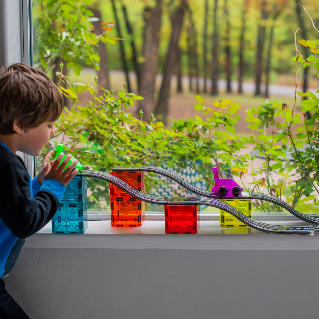 Child playing Magna-Tiles Downhill Duo by a window