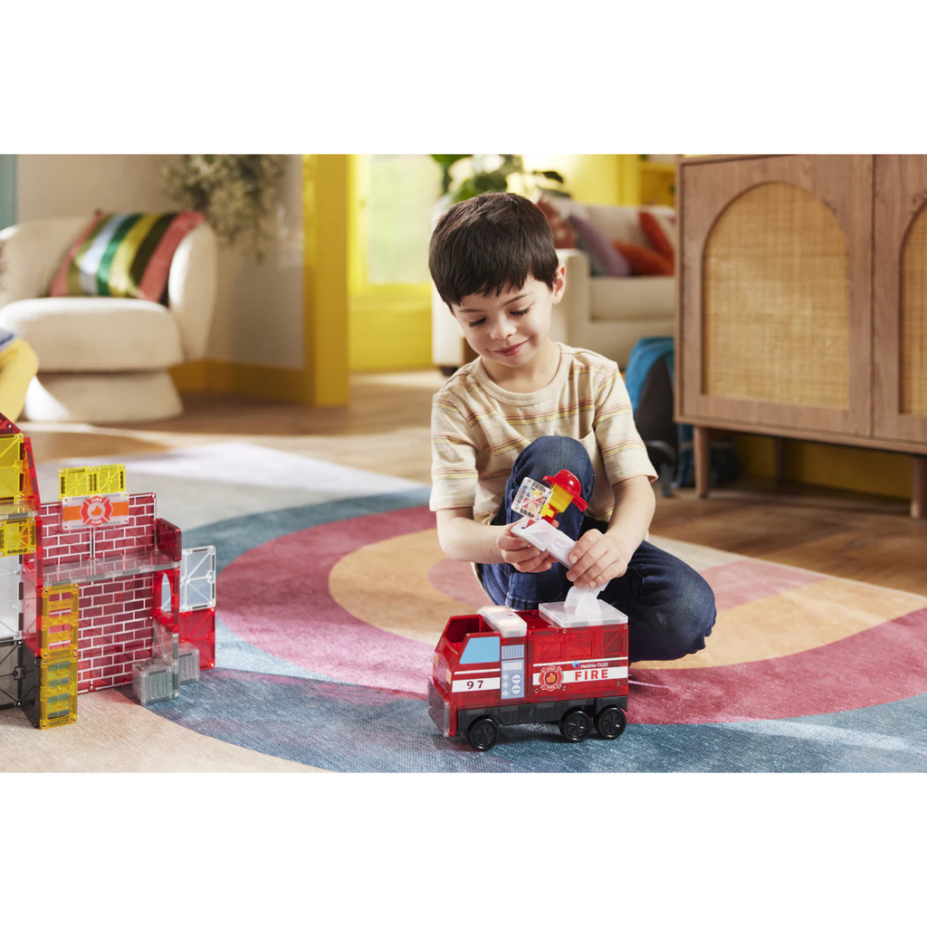 Child playing with a MagnaTiles fire truck in a living room.