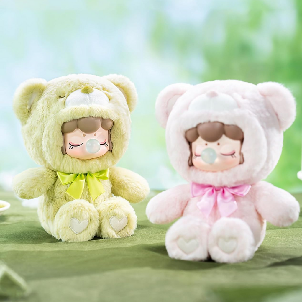 Two plush toys, one green and one pink, with cartoon faces on a green background.