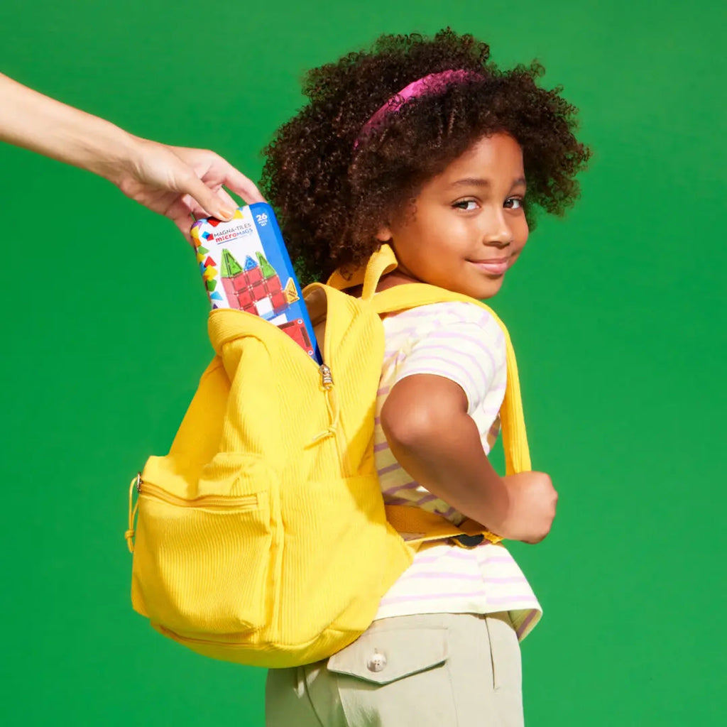 Hand putting microMAGS Travel Set into little girls backpack