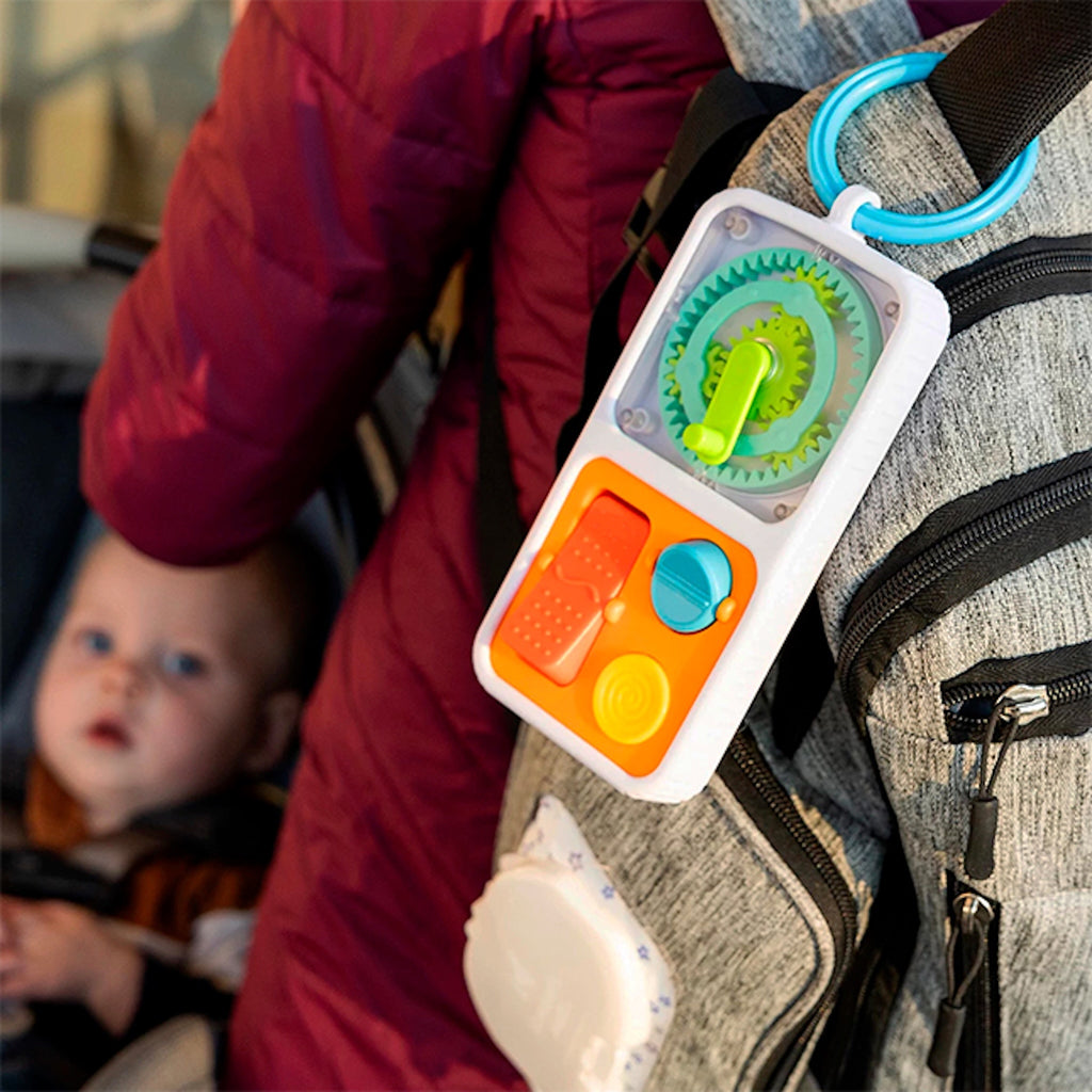 Colorful Play Tab Go attached to a backpack with a baby in the background