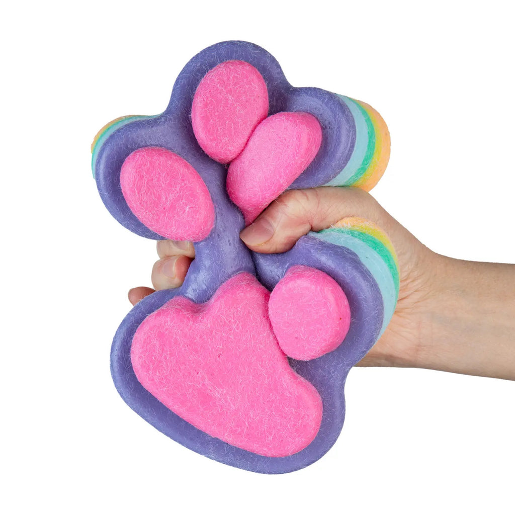 Hand holding a colorful paw-shaped Taba squishy against a white background