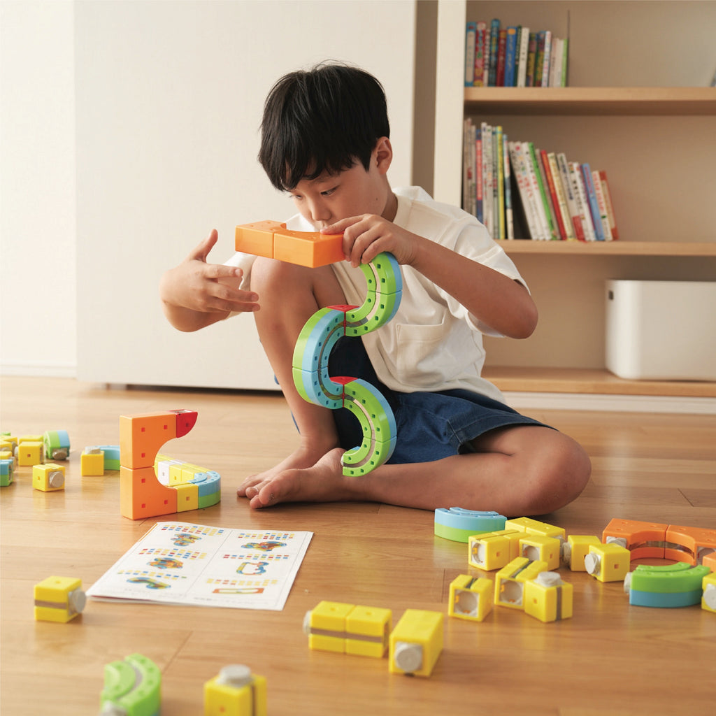 Child playing with colorful Rail Cube blocks on a wooden floor