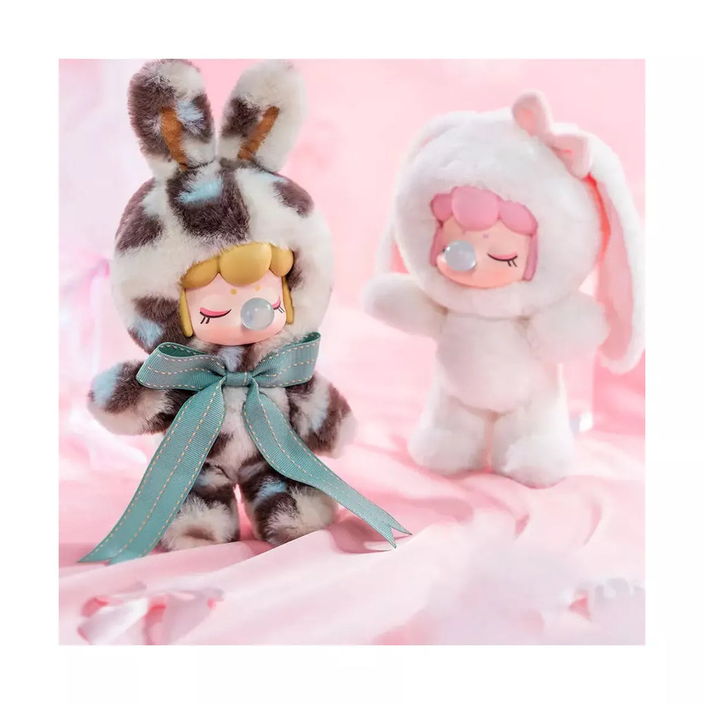 Two plush toys with bunny ears on a pink background