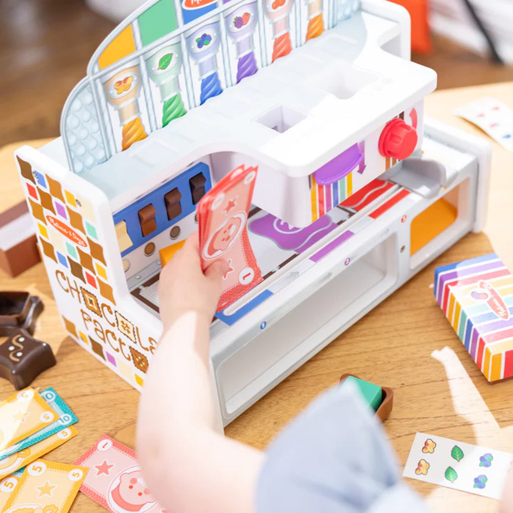 Colorful toy Chocolate Factory with pretend money on a wooden surface