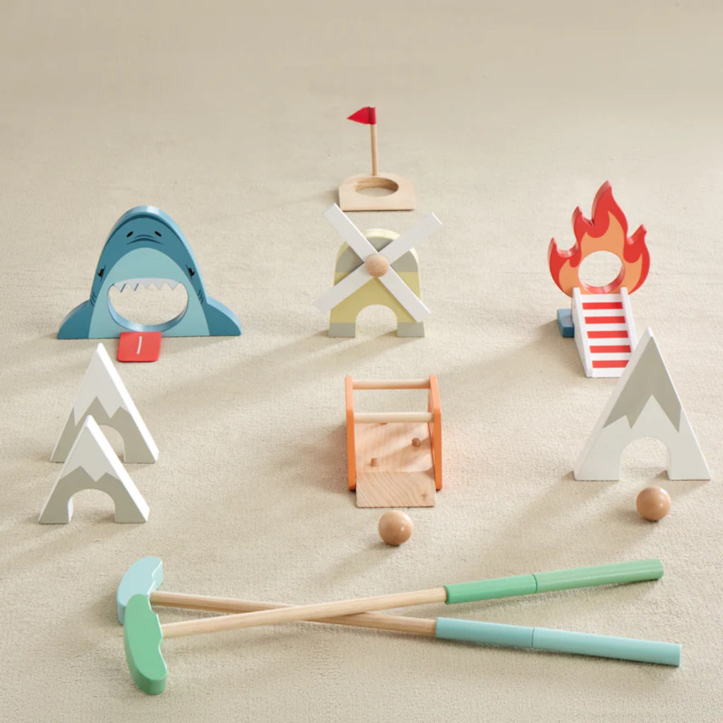 Set of colorful wooden Putt Putt Golf set including a shark, house, and campfire on a beige rug.