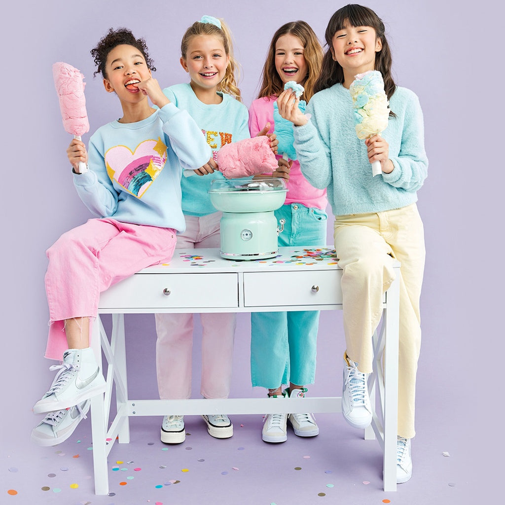 Girls standing around a table eating cotton candy