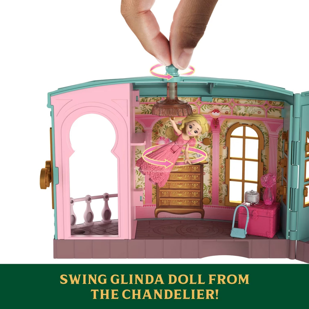 Toy dollhouse with a hand lifting a swing glinda doll from a chandelier