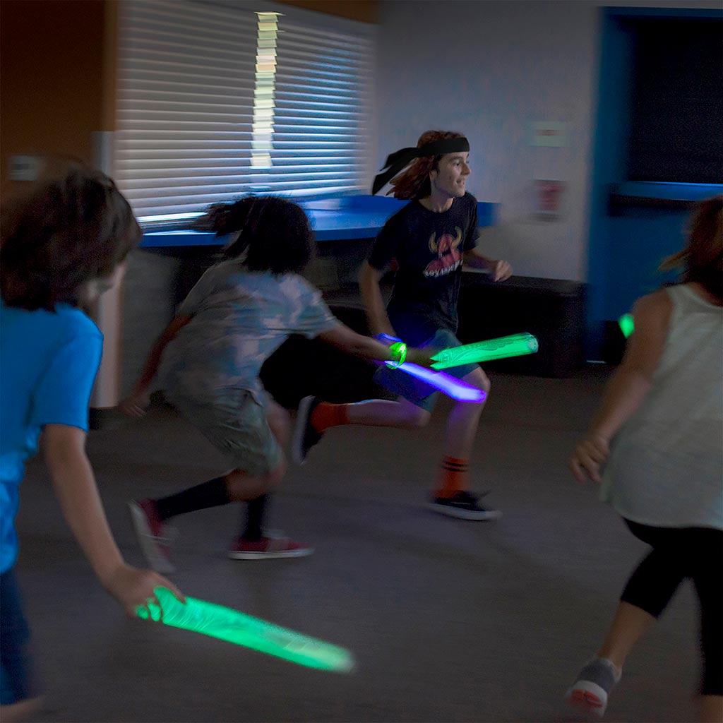 Kids Running Around Playing with Glow Foam Swords