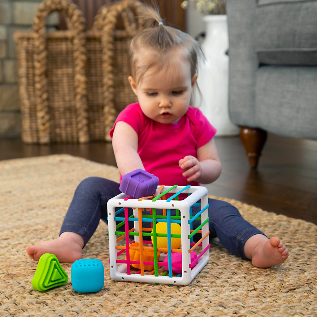 Child Sitting on Floor Putting Shaped Blocks Inside of InnyBin